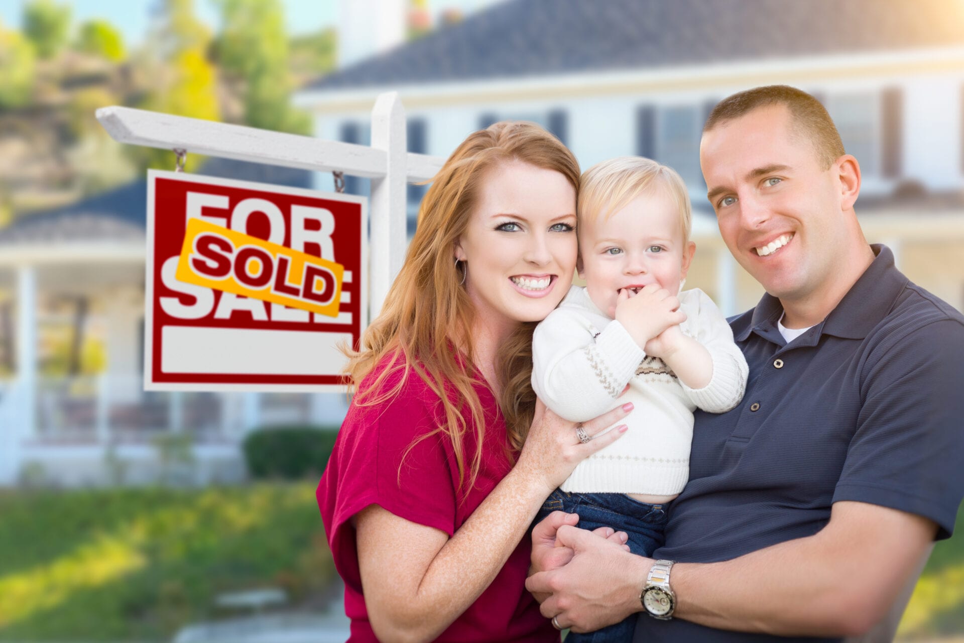 Happy Young Military Family in Front of Sold For Sale Real Estate Sign and New House. About home loans